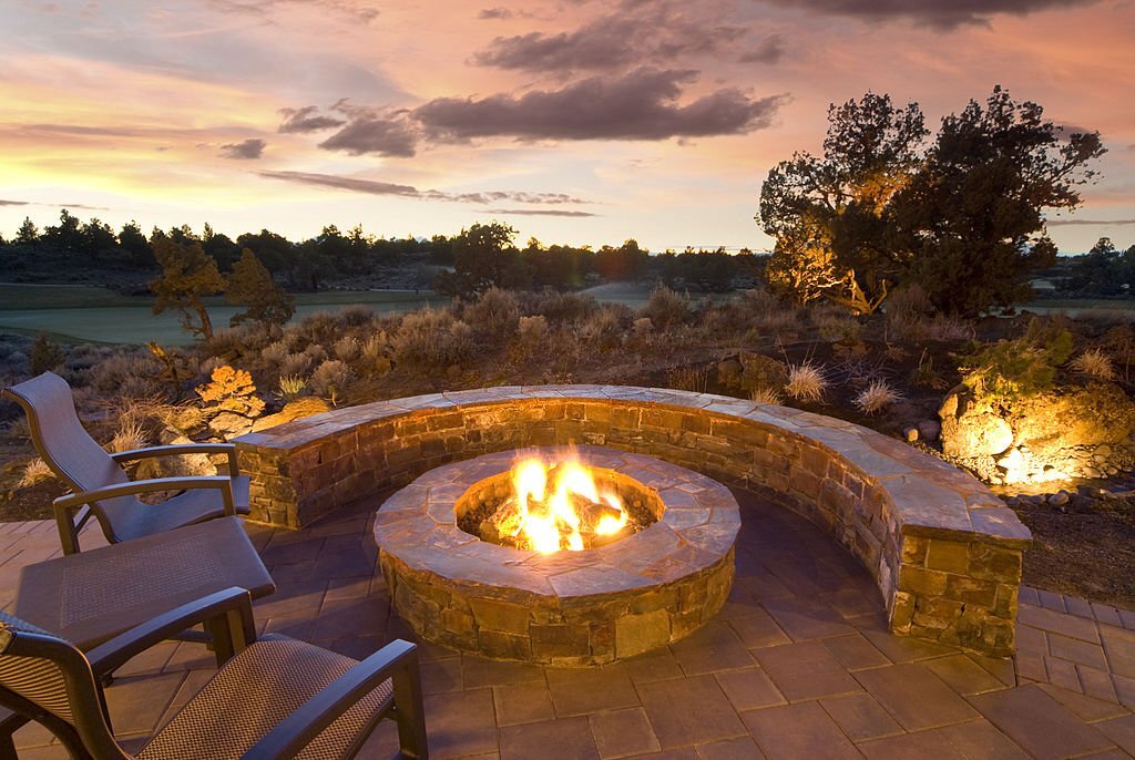 Circular stone fire pit with curved seating space at dusk