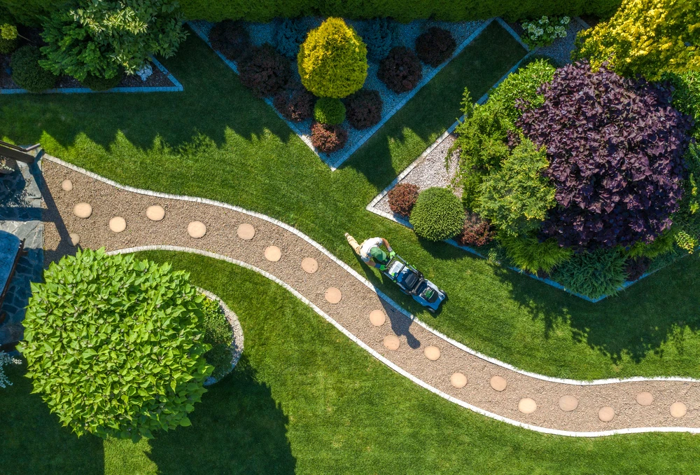 Aerial view of striped green lawn with curved stone path and landscaped beds showing neat lawn mowing patterns.